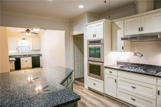 kitchen with white cabinetry, appliances with stainless steel finishes, ornamental molding, and dark stone countertops