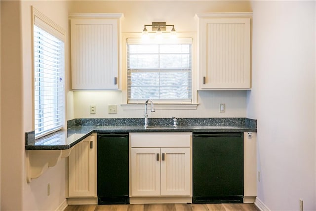 kitchen featuring sink, light wood-type flooring, dark stone countertops, dishwasher, and white cabinets