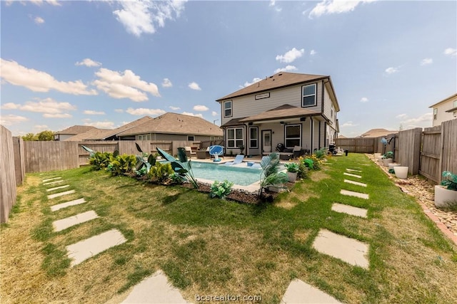 back of house featuring a fenced in pool and a lawn