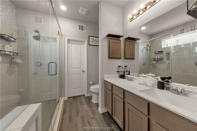 bathroom with hardwood / wood-style floors, vanity, an enclosed shower, and toilet