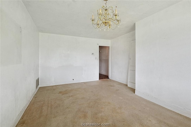 carpeted spare room with an inviting chandelier