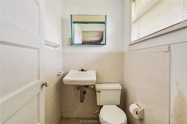 bathroom featuring sink, tile walls, and toilet