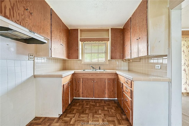 kitchen featuring backsplash, tile counters, dark parquet flooring, and sink