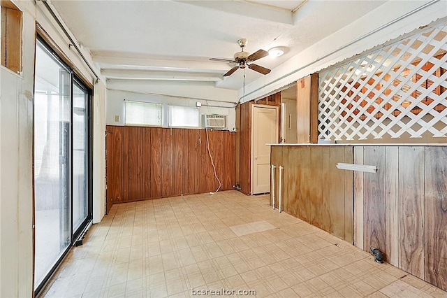 interior space featuring vaulted ceiling, ceiling fan, and wooden walls