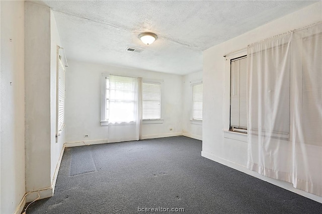 carpeted empty room featuring a textured ceiling