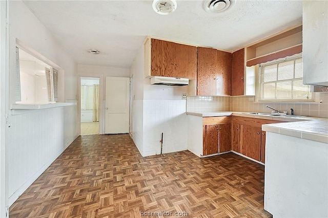 kitchen featuring dark parquet flooring, backsplash, and sink