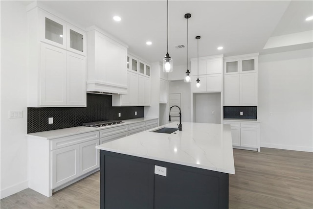 kitchen with visible vents, an island with sink, light wood-type flooring, stainless steel gas stovetop, and a sink