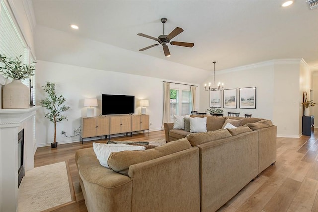 living area featuring a fireplace with flush hearth, light wood-style floors, ceiling fan with notable chandelier, and recessed lighting