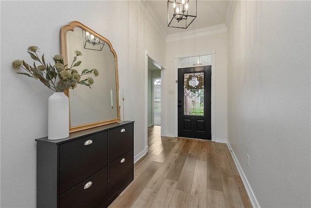 entryway featuring crown molding, baseboards, a notable chandelier, and light wood-style flooring