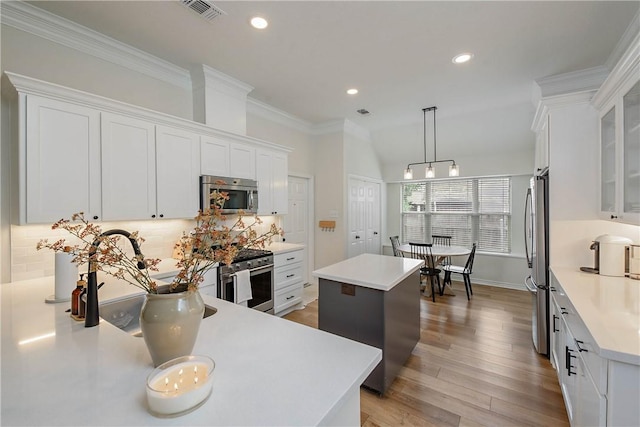 kitchen featuring a center island, light countertops, tasteful backsplash, a sink, and stainless steel appliances