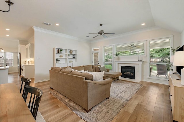 living area featuring visible vents, a fireplace with flush hearth, light wood-style flooring, and a ceiling fan