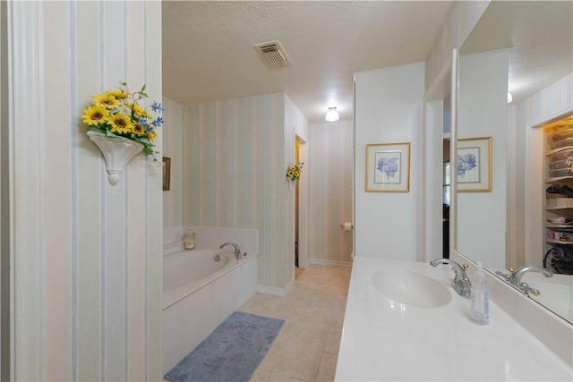 bathroom with tile patterned flooring, vanity, a bath, and a textured ceiling