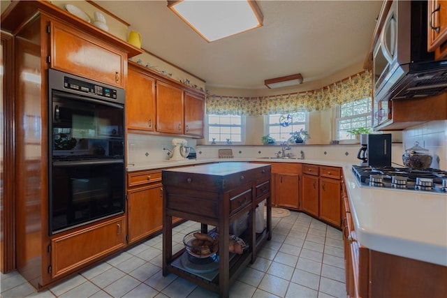 kitchen featuring stainless steel gas stovetop, backsplash, double oven, and light tile patterned flooring