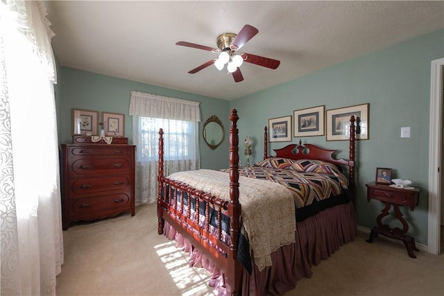 bedroom featuring light carpet, a textured ceiling, and ceiling fan