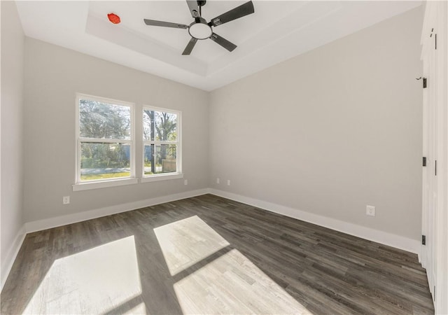 spare room featuring dark hardwood / wood-style floors, ceiling fan, and a tray ceiling