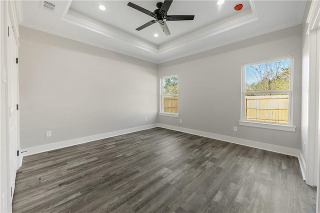 unfurnished room with a raised ceiling, ceiling fan, crown molding, and dark wood-type flooring