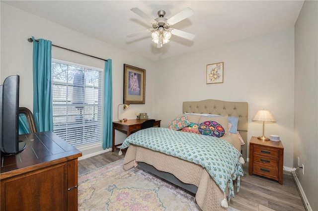 bedroom featuring a ceiling fan, baseboards, and wood finished floors