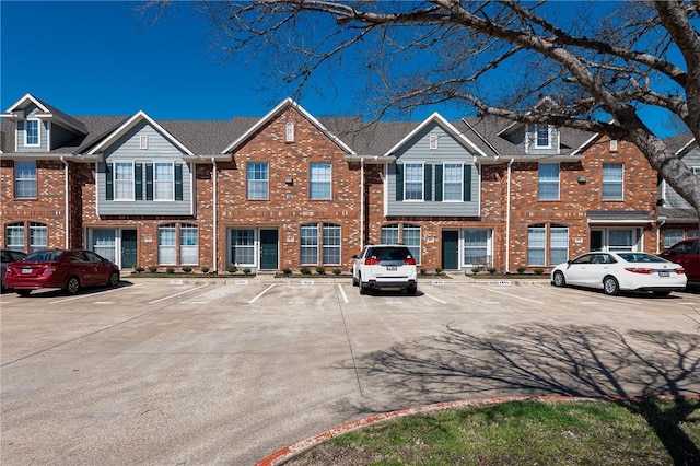 view of property featuring uncovered parking and brick siding