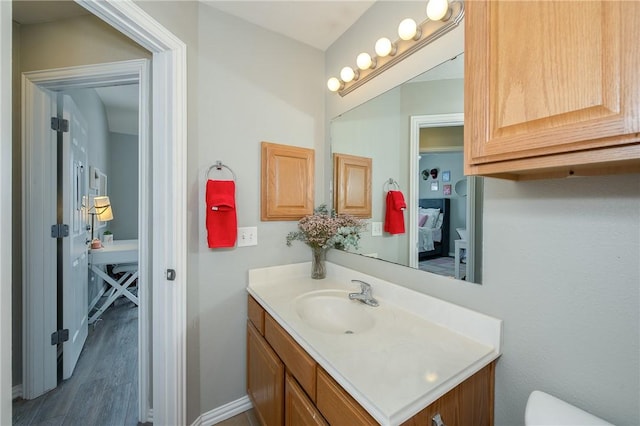 half bath featuring wood finished floors, vanity, and baseboards