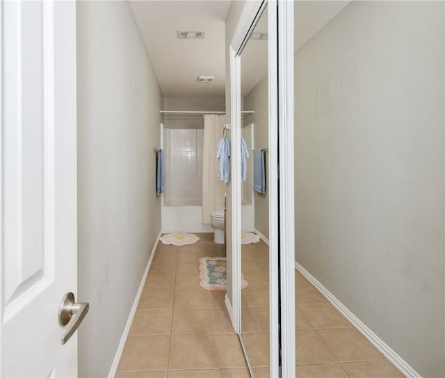 corridor with light tile patterned floors, visible vents, and baseboards