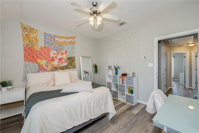 bedroom with dark wood finished floors, visible vents, attic access, ceiling fan, and baseboards