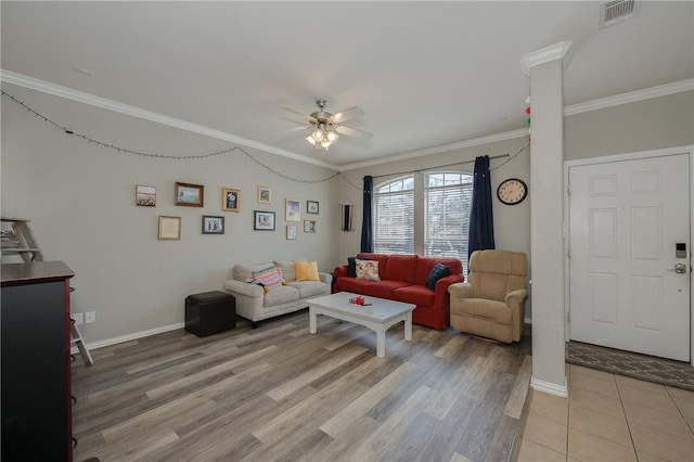 living area featuring ornate columns, a ceiling fan, visible vents, and crown molding