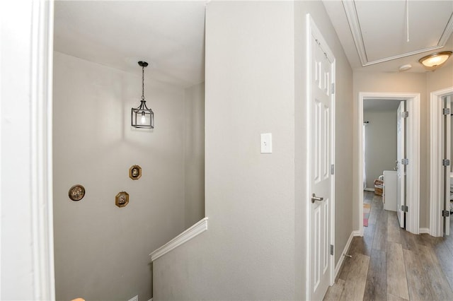 hall with attic access, light wood-style floors, and baseboards