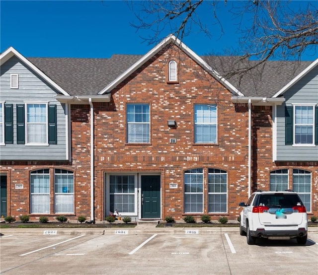 view of property featuring uncovered parking and brick siding