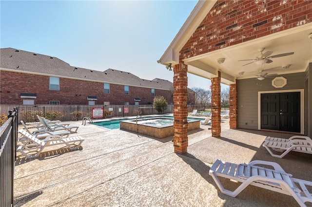 view of patio / terrace featuring a hot tub, a community pool, fence, and a ceiling fan