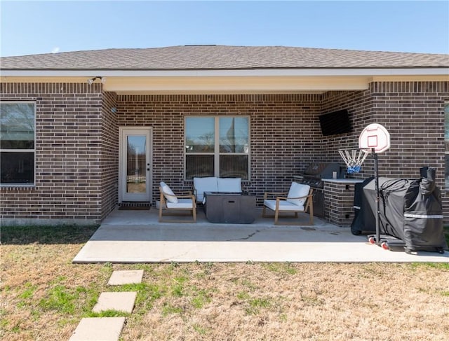 exterior space featuring a yard, a patio, brick siding, and a shingled roof