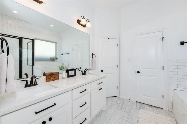 bathroom with marble finish floor, a sink, a shower stall, and double vanity