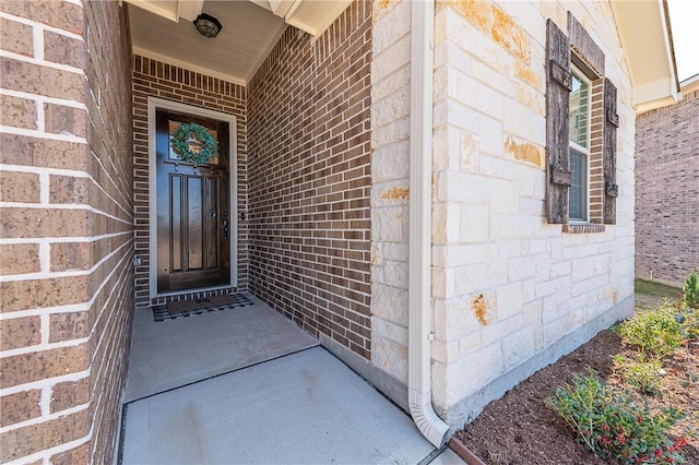 entrance to property featuring stone siding and brick siding