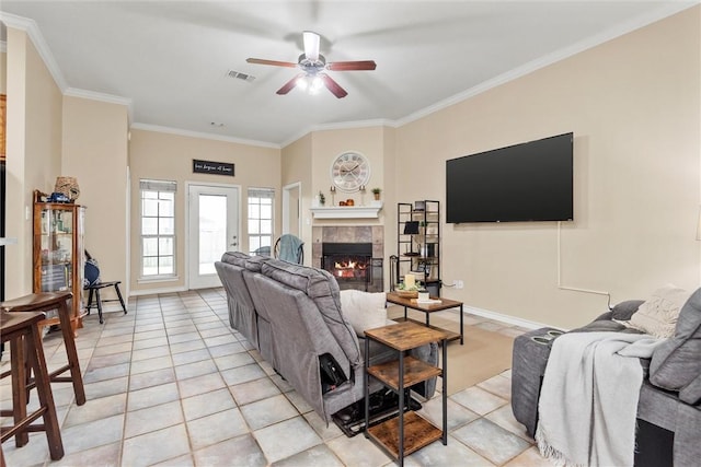 tiled living room with ceiling fan, crown molding, and a tiled fireplace