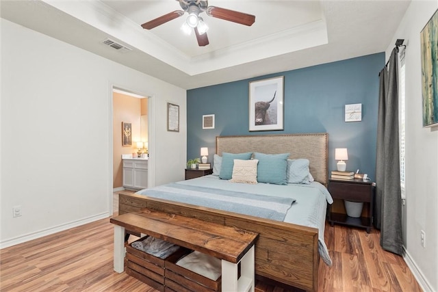 bedroom featuring hardwood / wood-style floors, ceiling fan, a raised ceiling, and connected bathroom