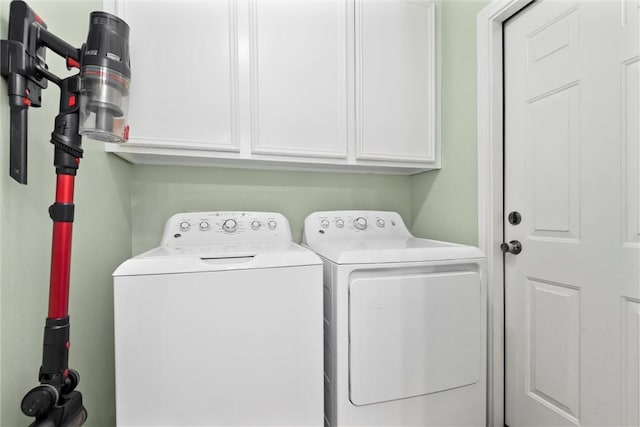 clothes washing area with separate washer and dryer and cabinets