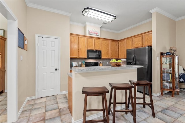 kitchen with a kitchen bar, a center island, ornamental molding, and black appliances