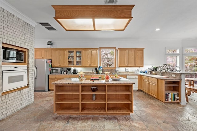 kitchen featuring brick wall, a kitchen island, sink, and white appliances