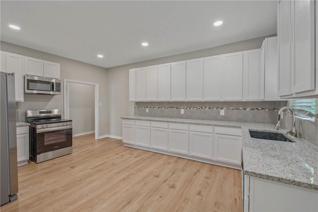 808 N Washington Ave, Bryan, TX 77803 - kitchen featuring stainless steel appliances, a sink, backsplash, light wood-style flooring, and recessed lighting