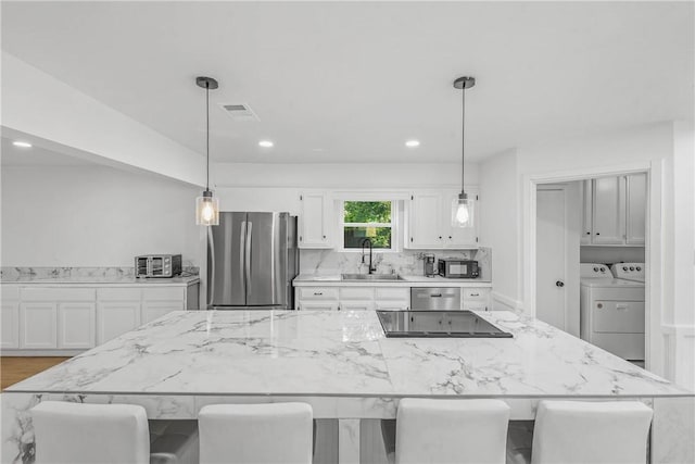 2430 E Briargate Dr, Bryan, TX 77802 - kitchen with black appliances, a sink, separate washer and dryer, white cabinets, and a breakfast bar