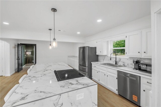 2430 E Briargate Dr, Bryan, TX 77802 - kitchen featuring appliances with stainless steel finishes, a sink, white cabinetry, decorative light fixtures, and light stone countertops