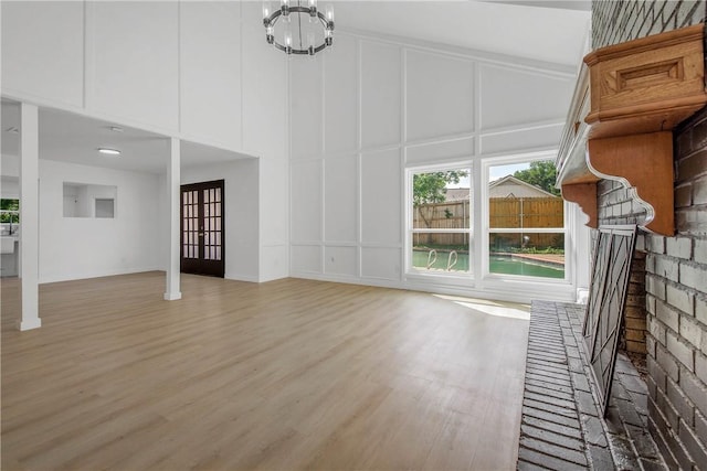 2430 E Briargate Dr, Bryan, TX 77802 - unfurnished living room with a decorative wall, light wood finished floors, a chandelier, and a high ceiling