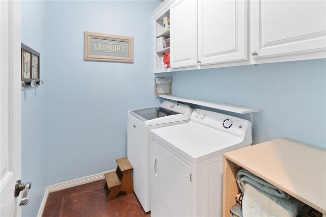 laundry room with dark tile patterned flooring, washer and dryer, and cabinets