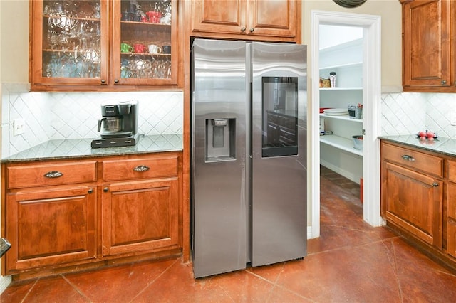 kitchen with decorative backsplash, stainless steel fridge with ice dispenser, dark tile patterned floors, and dark stone countertops