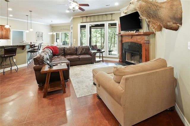 tiled living room with ceiling fan with notable chandelier and ornamental molding