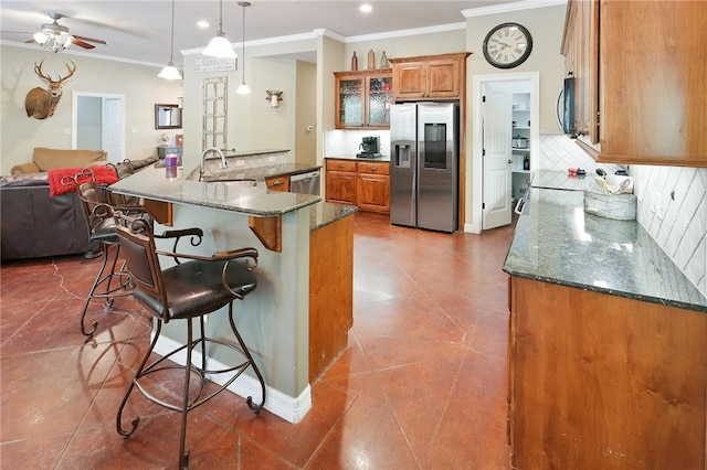 kitchen with backsplash, dark stone counters, pendant lighting, a kitchen bar, and appliances with stainless steel finishes