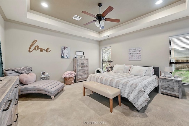 carpeted bedroom featuring ceiling fan, a raised ceiling, and crown molding