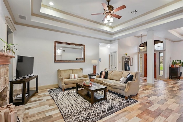 living room featuring a tray ceiling, light hardwood / wood-style flooring, ceiling fan, and crown molding