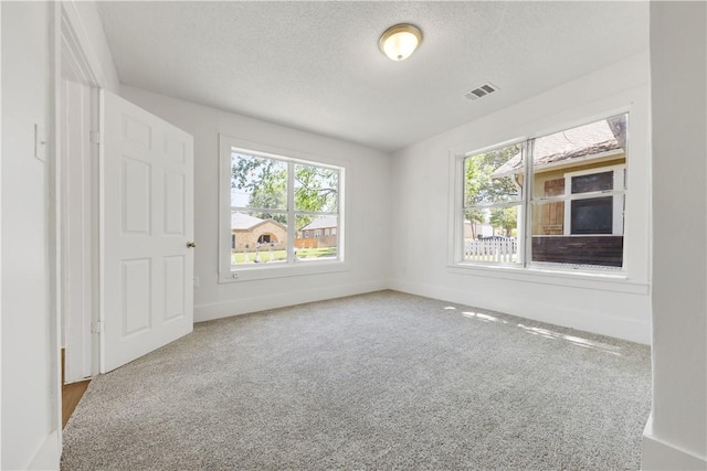 empty room featuring visible vents, a healthy amount of sunlight, and carpet floors