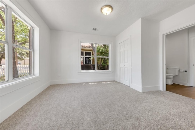 unfurnished bedroom with carpet, visible vents, baseboards, and a closet
