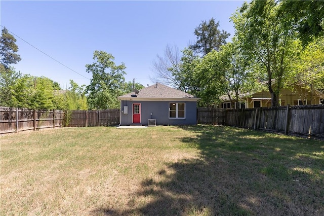 rear view of house with a yard, cooling unit, stucco siding, and a fenced backyard